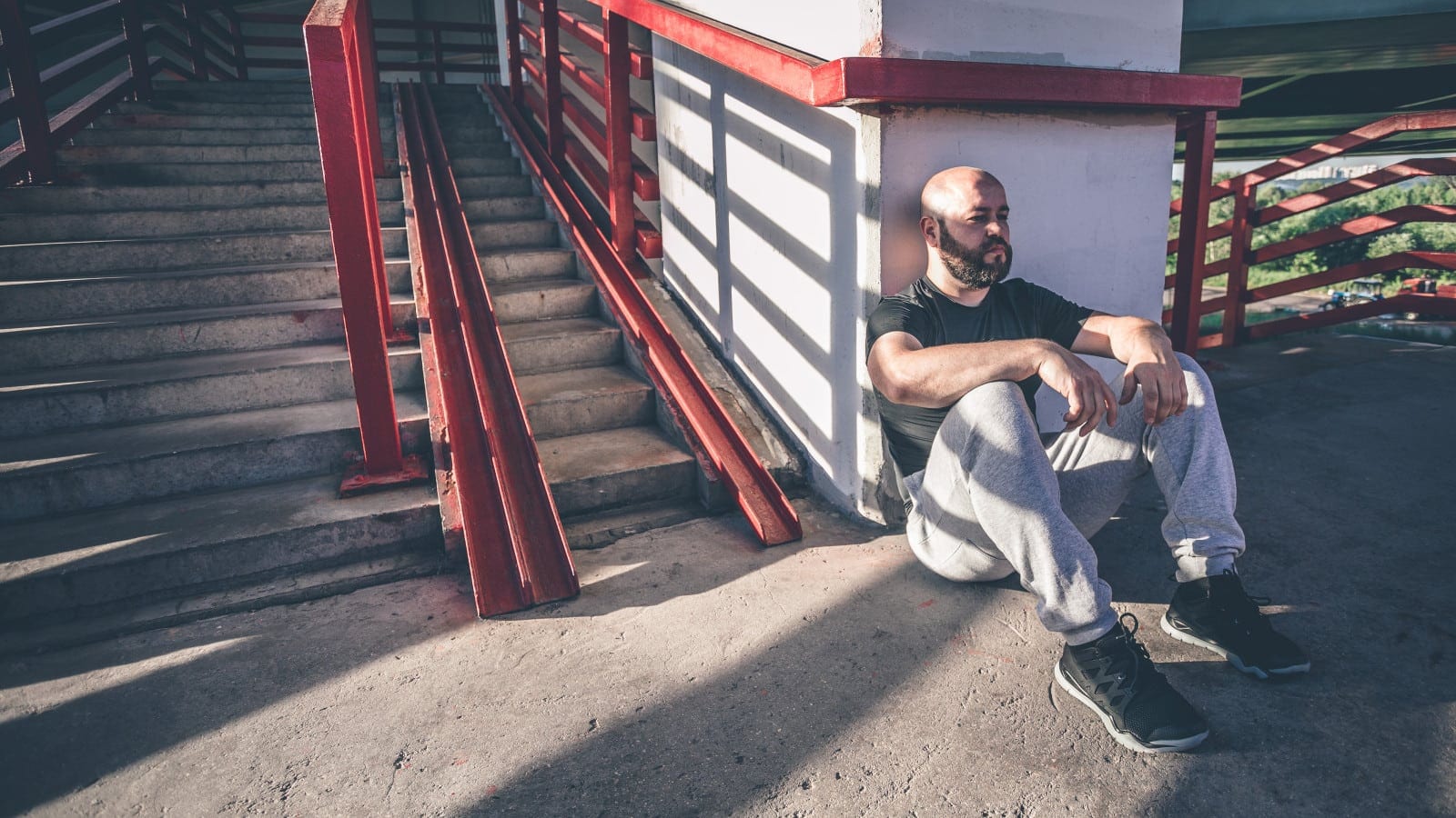 Bald Man Sitting On The Ground By Himself Stock Photo
