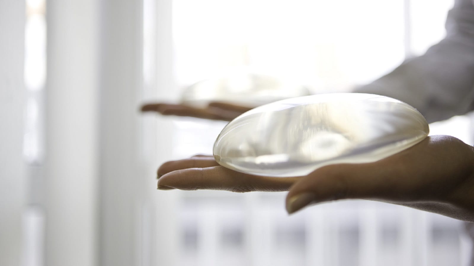 Surgeon Holding Two Breast Implants