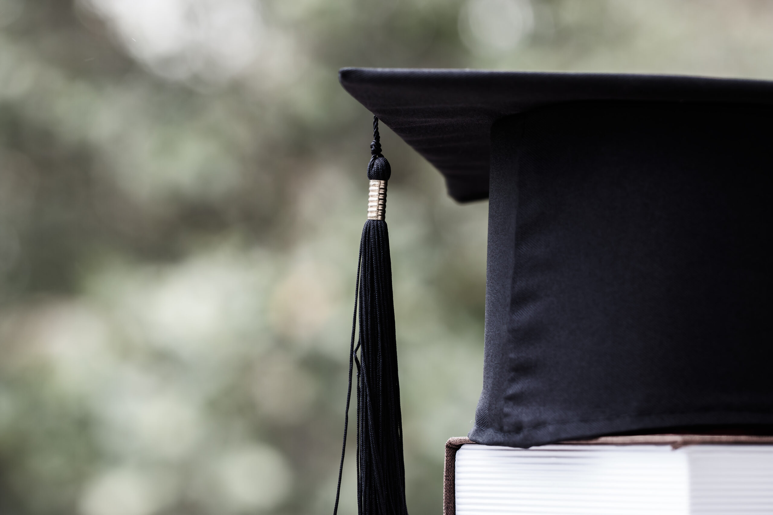 graduation cap sitting on top of college textbooks