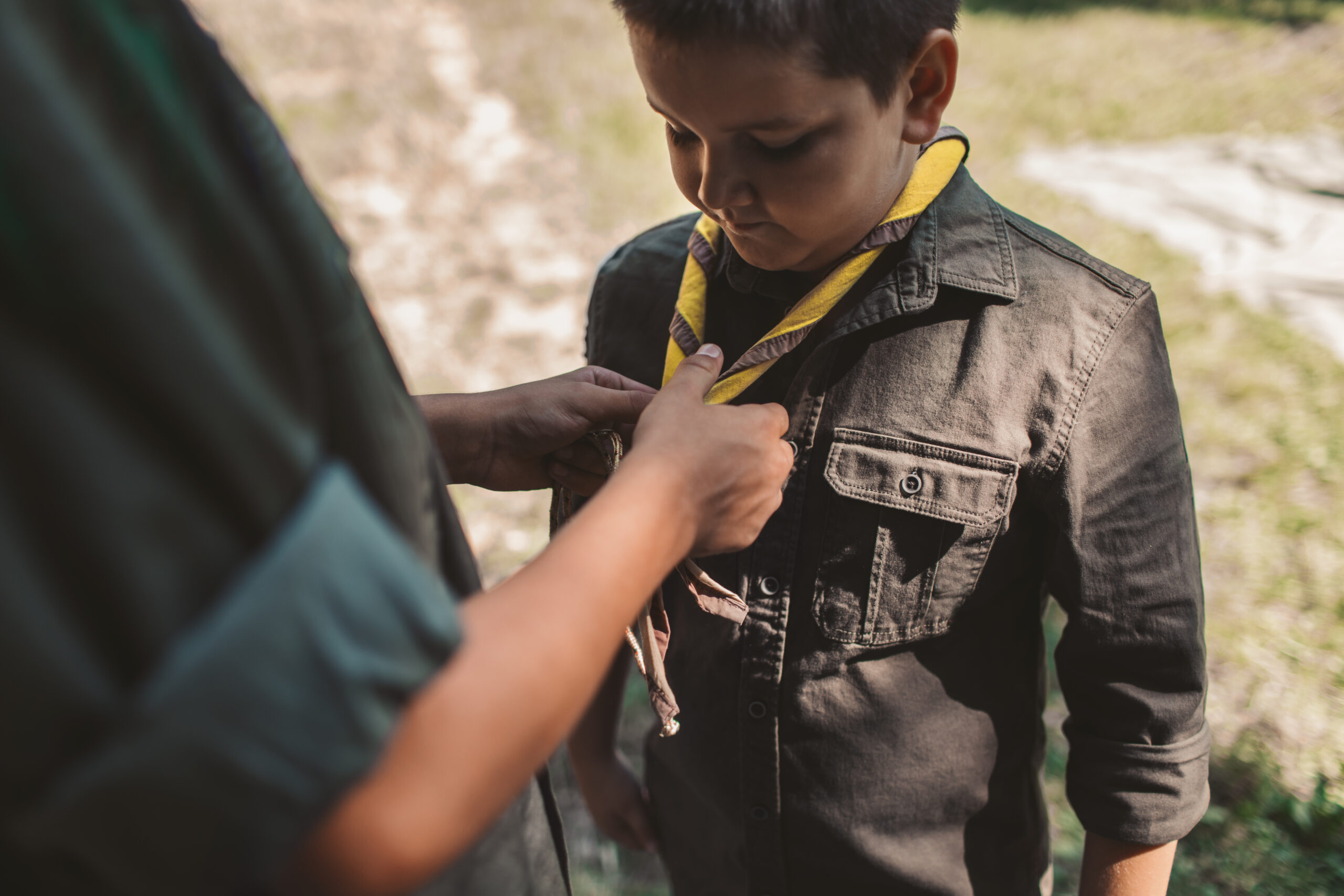 boy scout having his scarf tied by scout leader